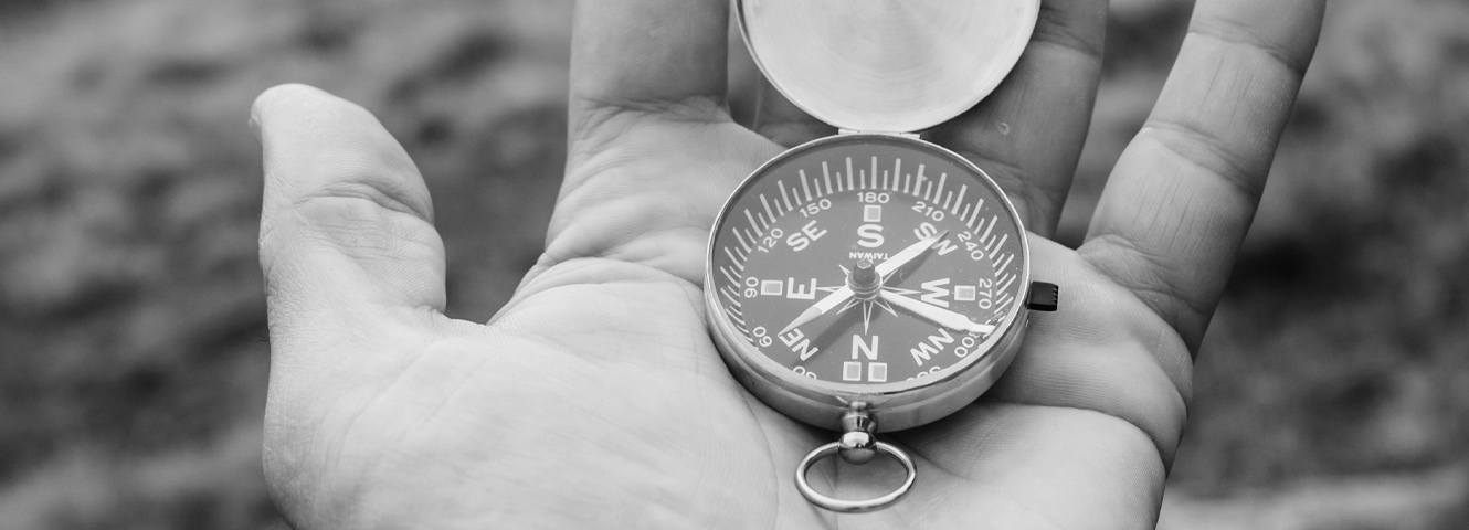 A closely cropped in image of a hand holding a compass.